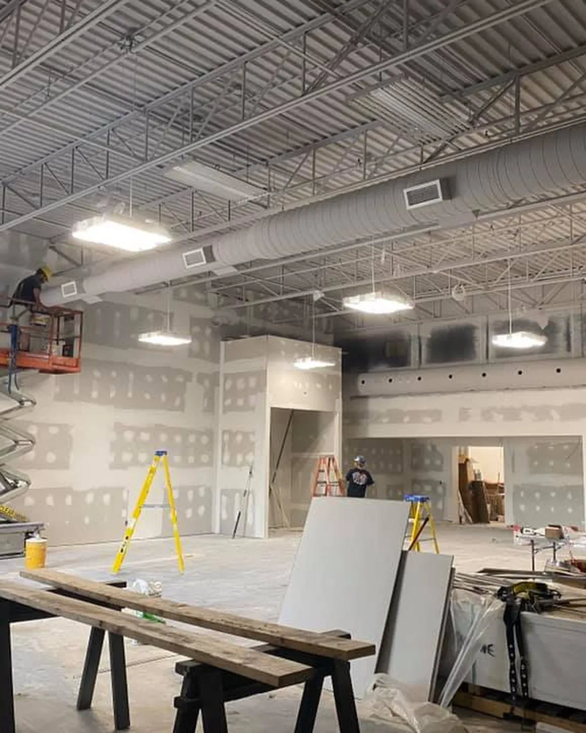 Electrician on a scissor lift installing lighting in a commercial space